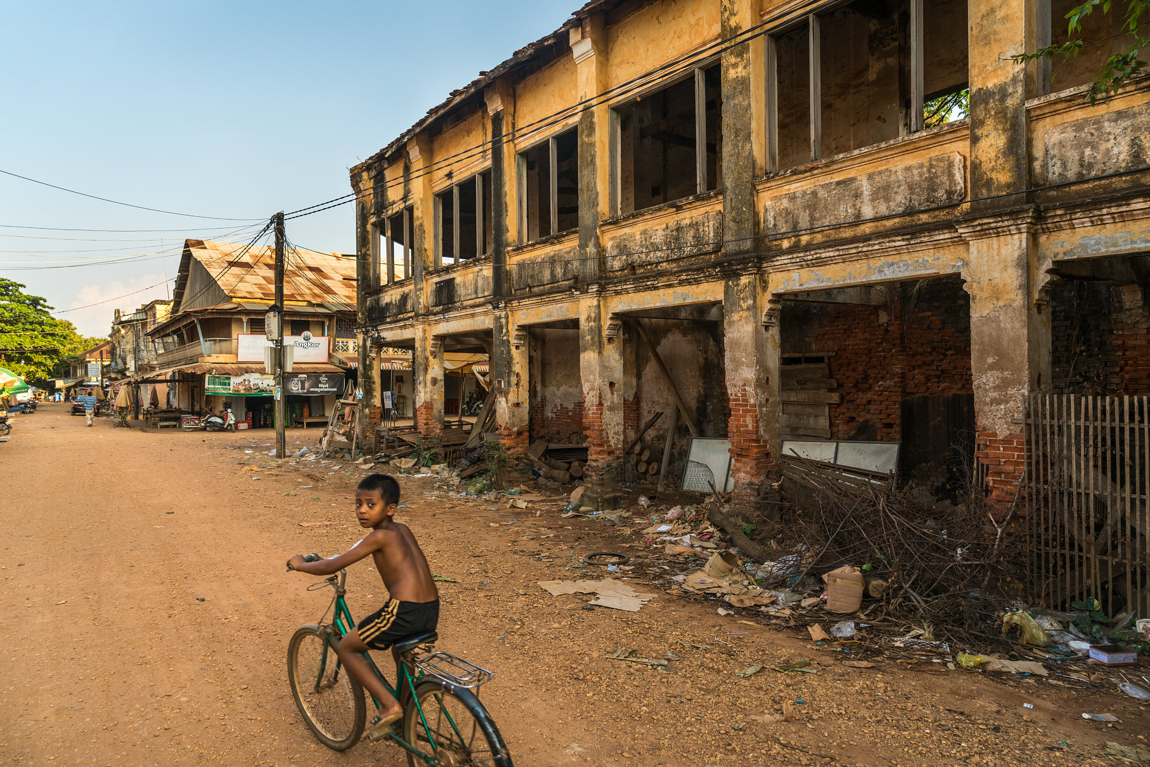 Kid on bike and crumbling old colonial buildings in Chhlong town, Kratie province, Cambodia