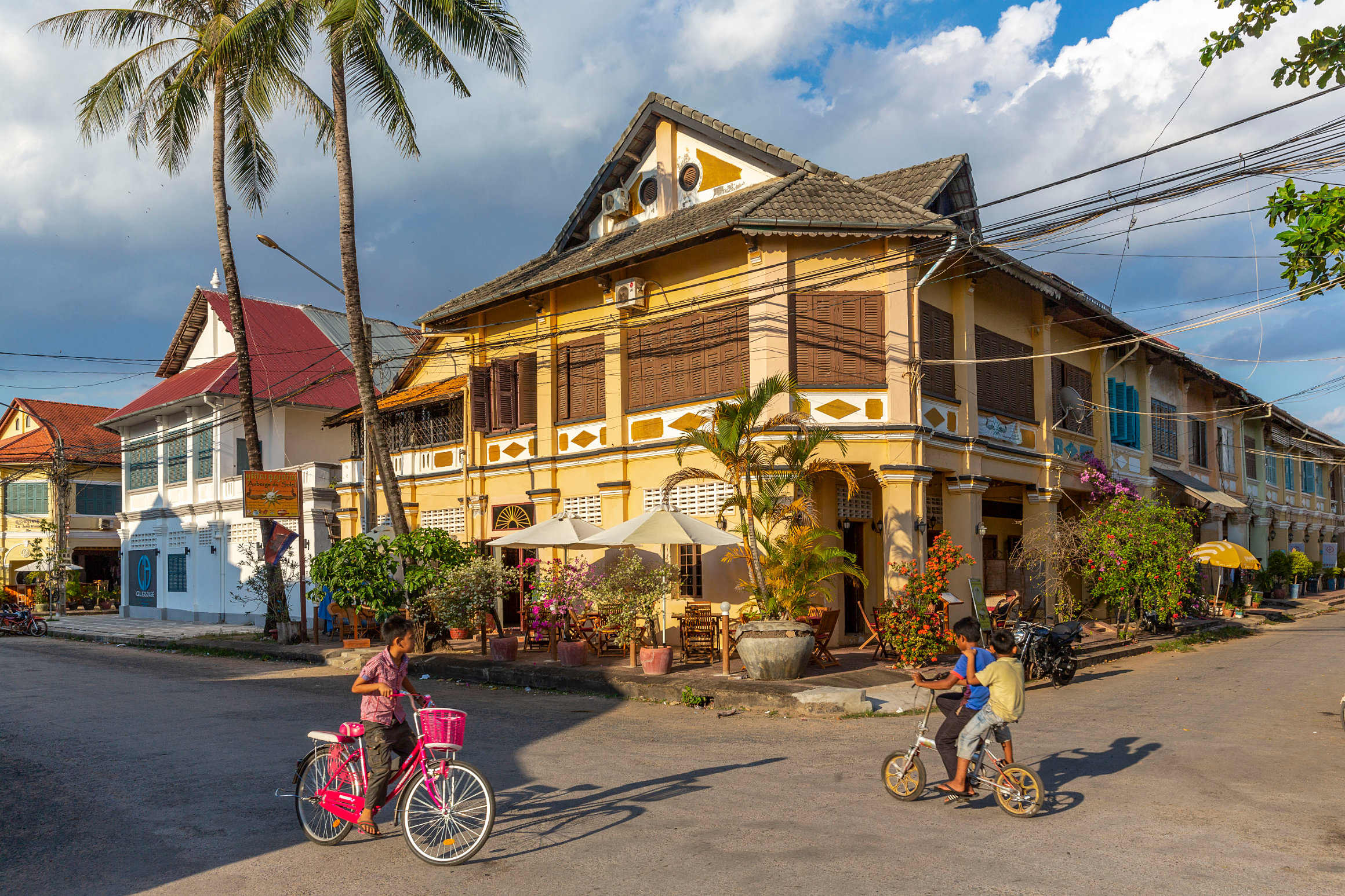 Charming colonial building and kids on bikes in Kampot, Cambodia